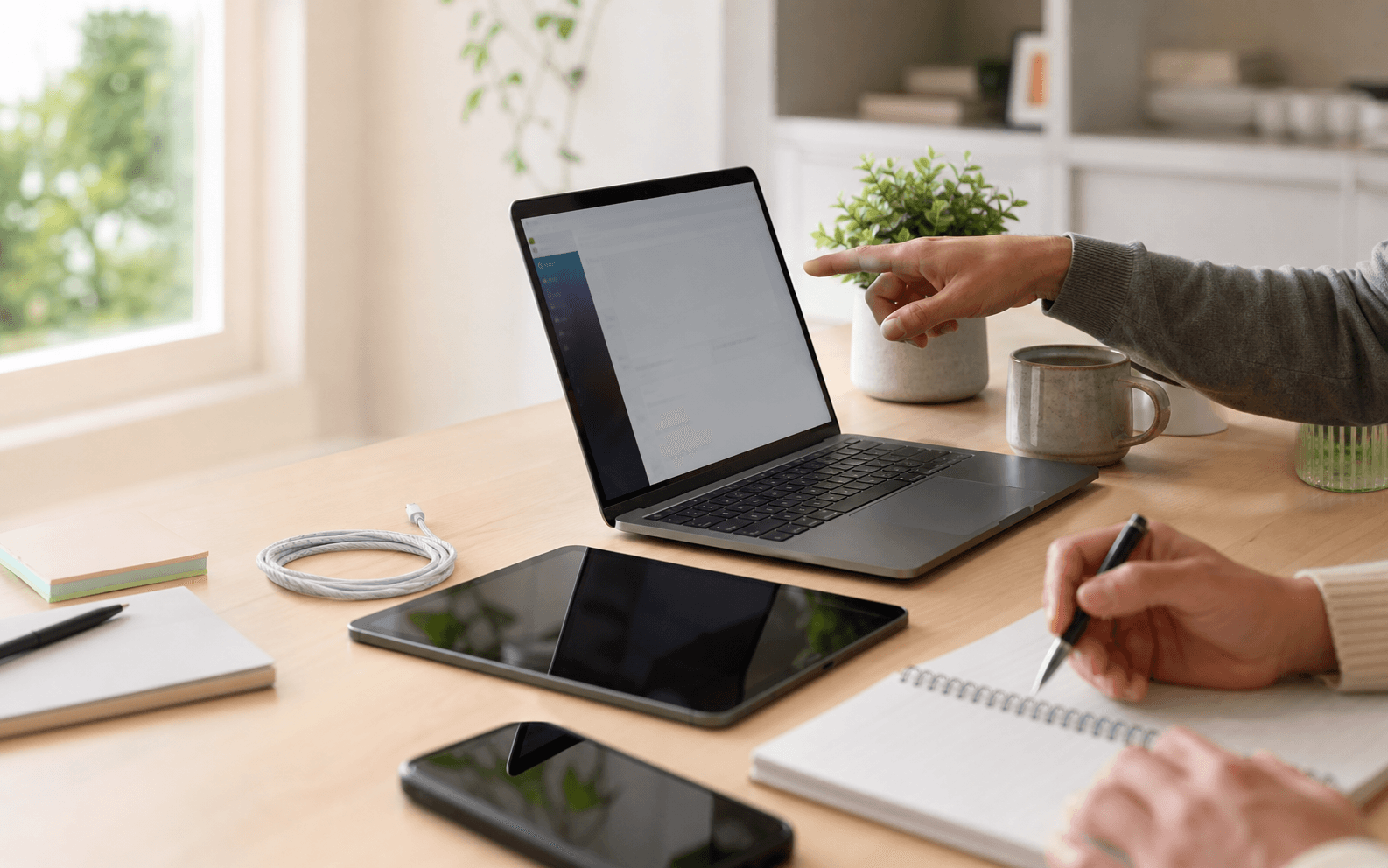 A coaching session with a laptop, tablet, phone, and notebook on a desk